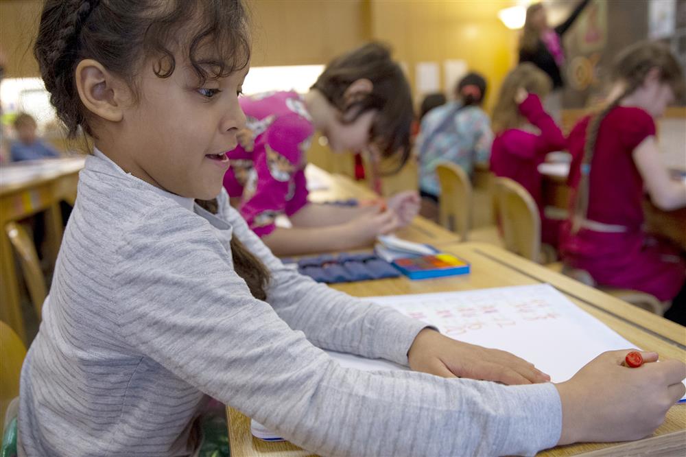 A student writes multiplication problems in her Main lesson book during math instruction at Winterberry Charter School. 